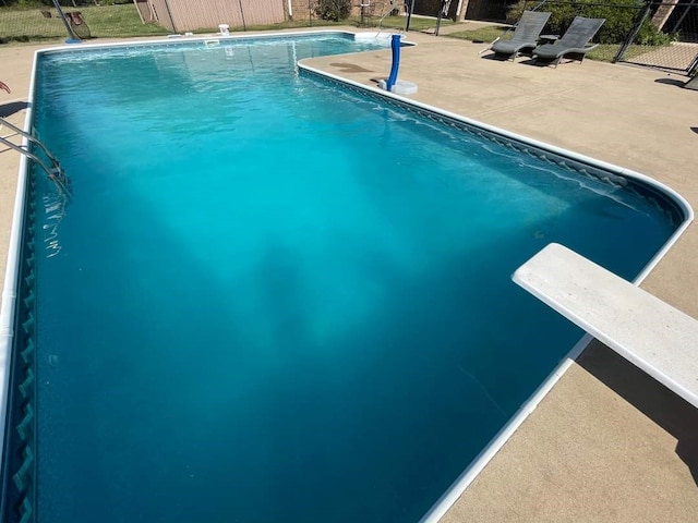 view of swimming pool featuring a patio area and a diving board