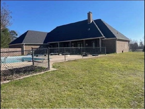 back of property featuring a fenced in pool and a yard