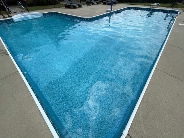 view of pool with a diving board and a patio