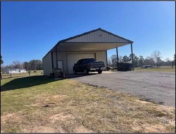 view of outdoor structure with a garage, a yard, and a carport