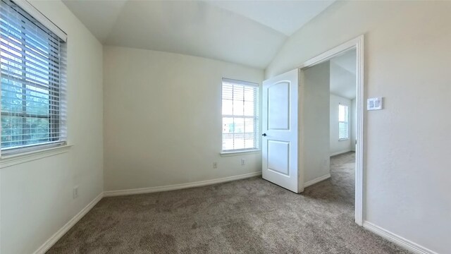 unfurnished bedroom featuring vaulted ceiling and light carpet