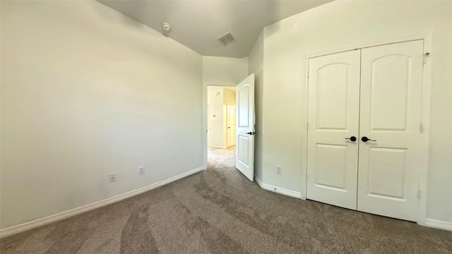 unfurnished bedroom featuring lofted ceiling, visible vents, baseboards, a closet, and carpet