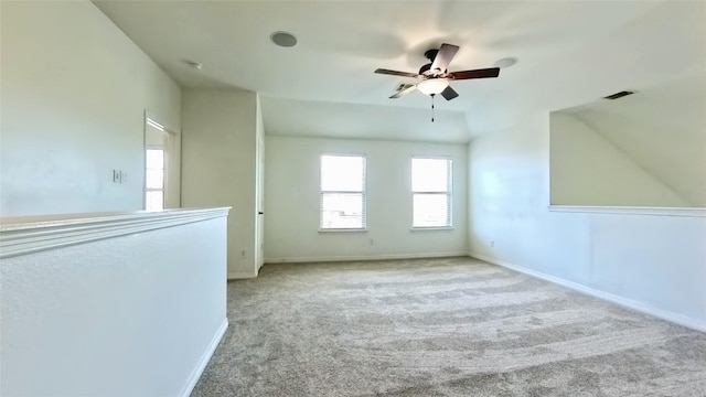 carpeted spare room with visible vents, baseboards, and a ceiling fan