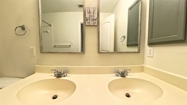 bathroom with double vanity, visible vents, toilet, and a sink