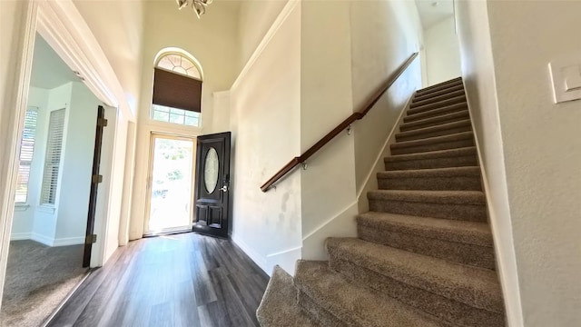 foyer entrance featuring baseboards, a high ceiling, stairway, and dark wood finished floors