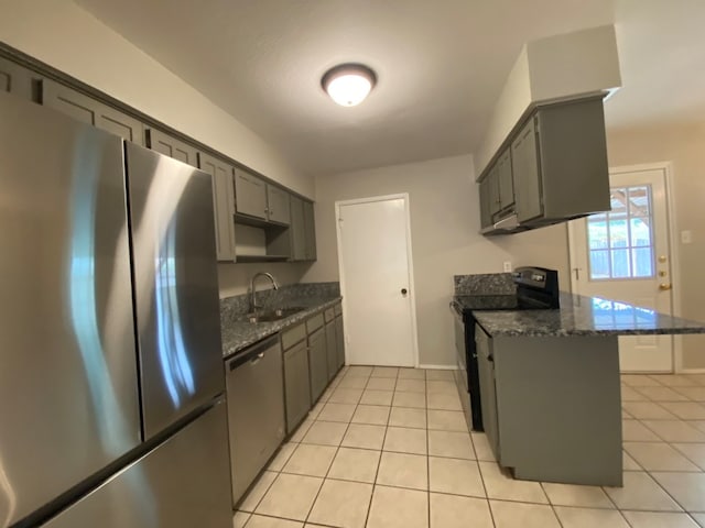 kitchen featuring dark stone counters, a kitchen bar, sink, appliances with stainless steel finishes, and light tile patterned flooring