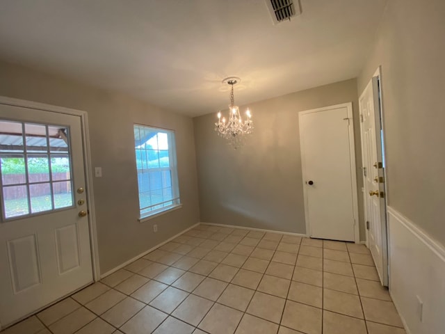 doorway to outside with a notable chandelier and light tile patterned floors