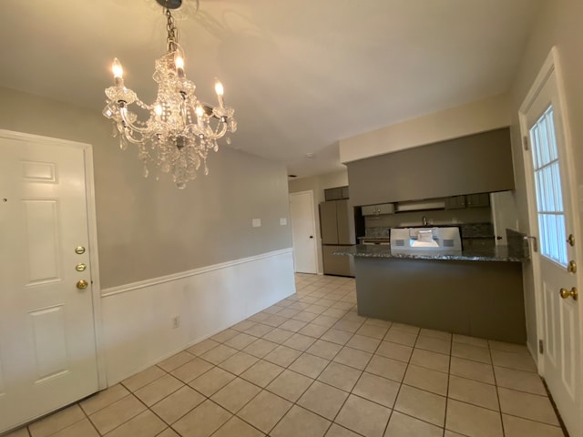 kitchen with an inviting chandelier, dark stone counters, and light tile patterned flooring