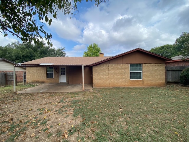 back of property with a lawn and a patio