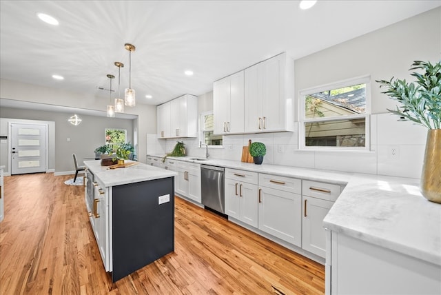 kitchen with plenty of natural light, light hardwood / wood-style floors, white cabinetry, and stainless steel dishwasher