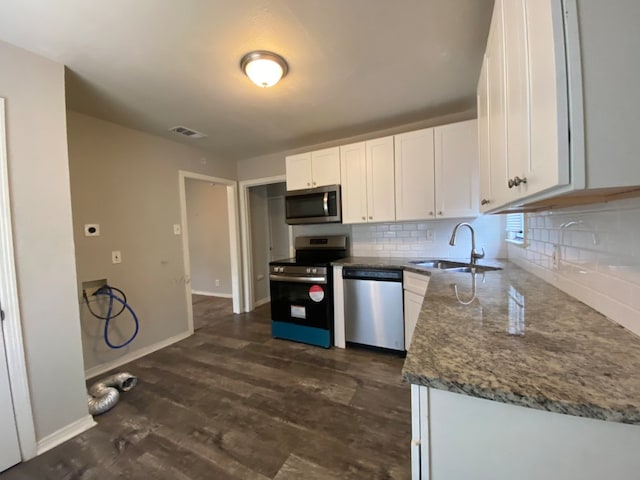 kitchen with dark hardwood / wood-style floors, appliances with stainless steel finishes, white cabinets, sink, and stone counters