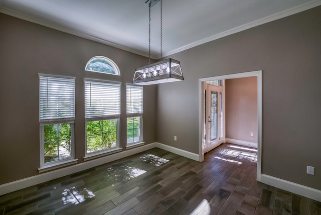 unfurnished dining area featuring ornamental molding, dark wood-type flooring, and a chandelier