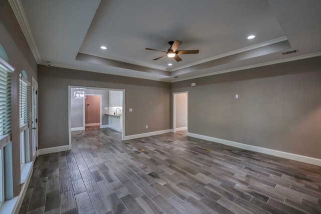 spare room with a tray ceiling, ornamental molding, ceiling fan, and dark hardwood / wood-style floors