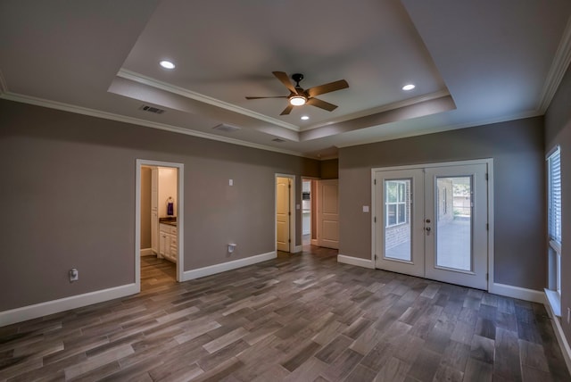 empty room with dark wood-type flooring, a tray ceiling, ceiling fan, and crown molding