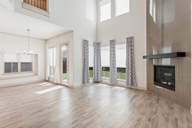 unfurnished living room featuring a tile fireplace, light hardwood / wood-style floors, and a healthy amount of sunlight