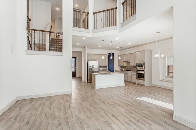 unfurnished living room featuring ornamental molding, a chandelier, and light hardwood / wood-style floors