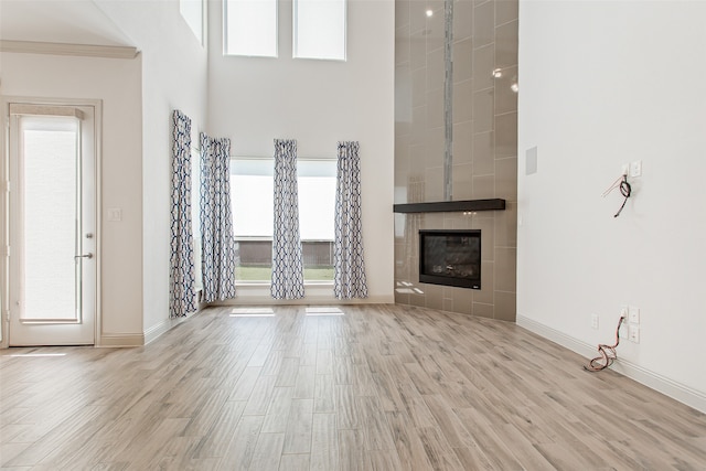 unfurnished living room featuring a wealth of natural light, a tile fireplace, and light hardwood / wood-style floors