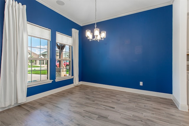 empty room featuring light wood-type flooring, ornamental molding, and a chandelier