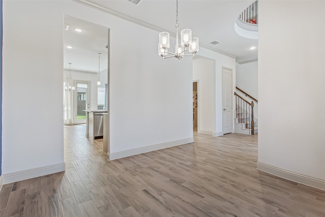 unfurnished dining area with ornamental molding, a notable chandelier, and light hardwood / wood-style floors