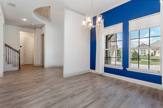 empty room with ornamental molding, a chandelier, and hardwood / wood-style flooring