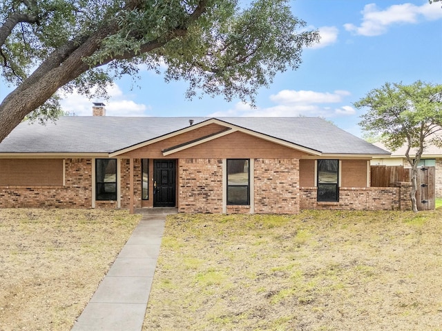 ranch-style home featuring a front yard, brick siding, a chimney, and fence