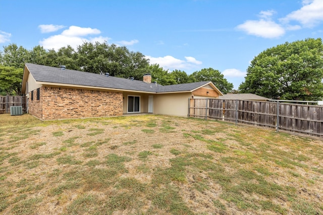 back of house with a yard and central AC