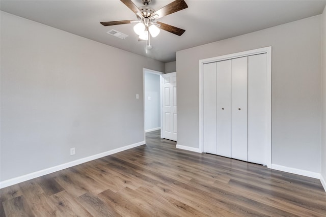 unfurnished bedroom featuring dark wood-type flooring, ceiling fan, and a closet