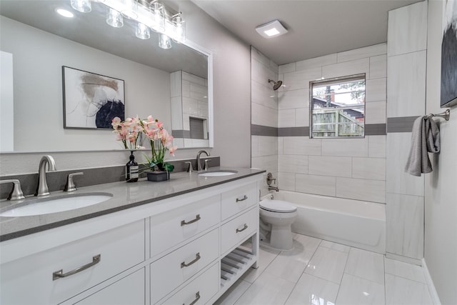 full bathroom featuring tiled shower / bath, vanity, and toilet