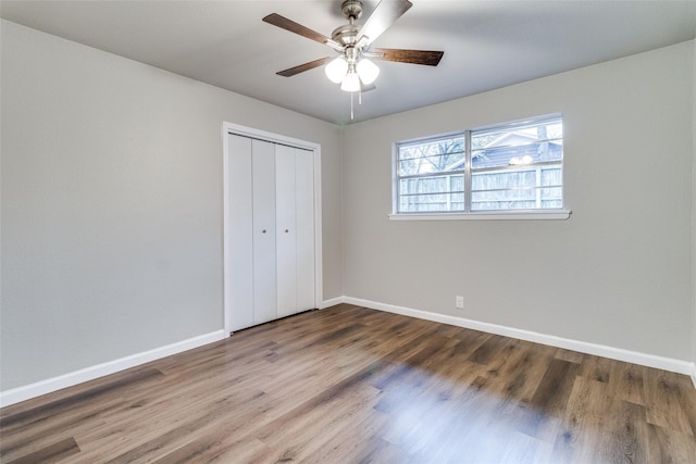 unfurnished bedroom featuring hardwood / wood-style floors, ceiling fan, and a closet