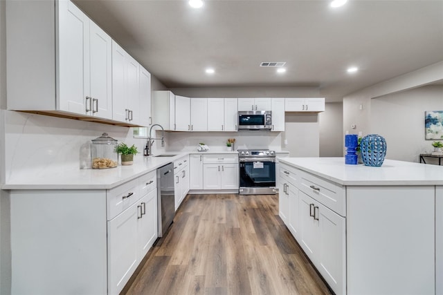 kitchen featuring white cabinets, hardwood / wood-style floors, stainless steel appliances, sink, and decorative backsplash