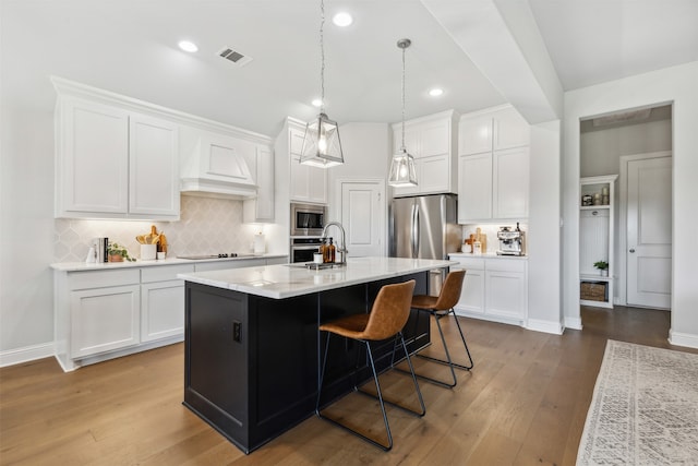 kitchen featuring stainless steel appliances, a center island with sink, and white cabinets