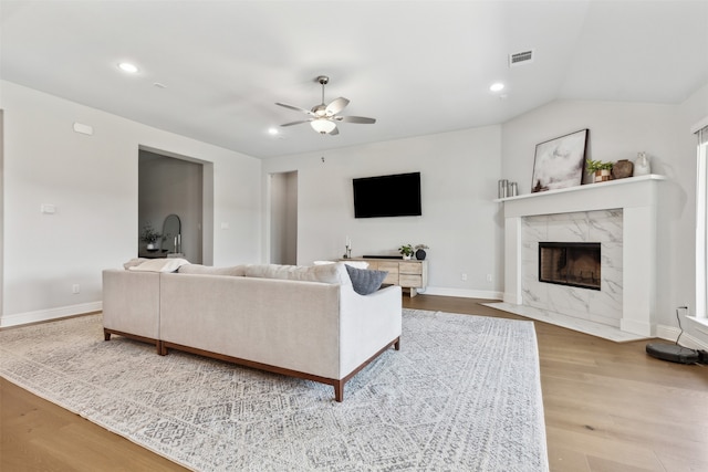 living room with lofted ceiling, a fireplace, light hardwood / wood-style flooring, and ceiling fan