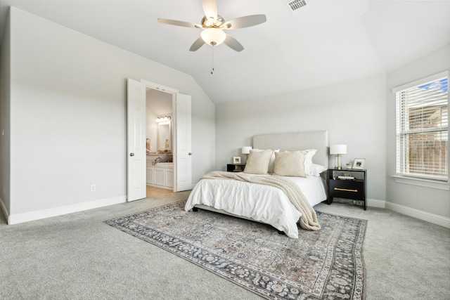 bedroom featuring lofted ceiling, ensuite bath, light carpet, and ceiling fan