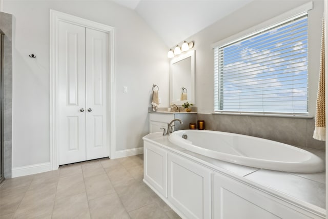 bathroom featuring tile patterned floors, vaulted ceiling, and a washtub