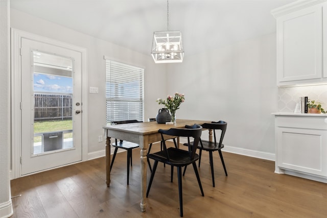 dining space with dark hardwood / wood-style flooring and a chandelier