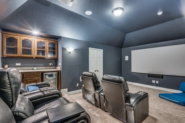 carpeted home theater room with lofted ceiling, beverage cooler, and indoor bar