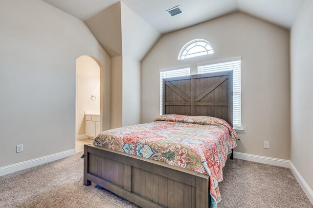 carpeted bedroom featuring lofted ceiling and connected bathroom