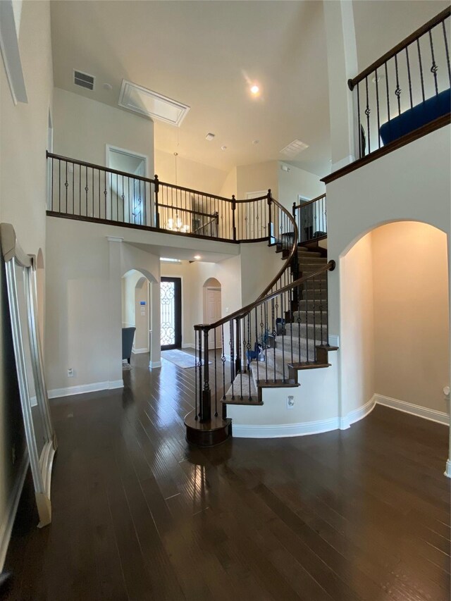 staircase with hardwood / wood-style flooring and a towering ceiling