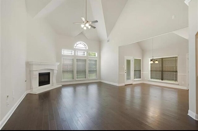 unfurnished living room with ceiling fan with notable chandelier, a healthy amount of sunlight, and dark hardwood / wood-style floors