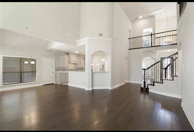 unfurnished living room with dark wood-type flooring and a towering ceiling