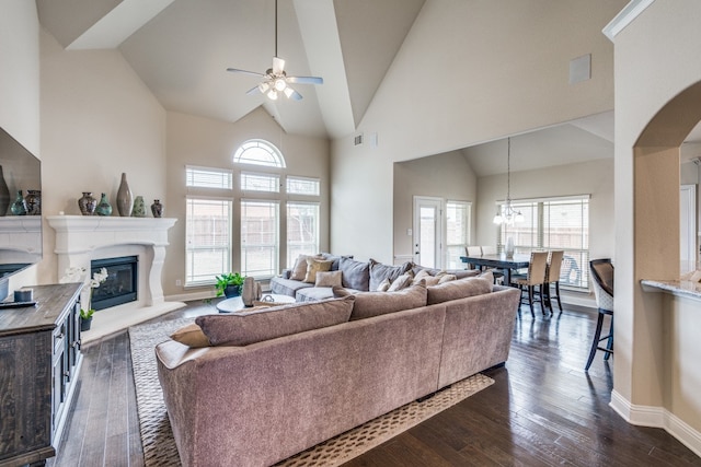 living room with ceiling fan with notable chandelier, high vaulted ceiling, and dark hardwood / wood-style flooring