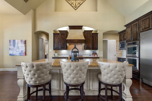 kitchen featuring high vaulted ceiling, stainless steel appliances, custom exhaust hood, and a kitchen island