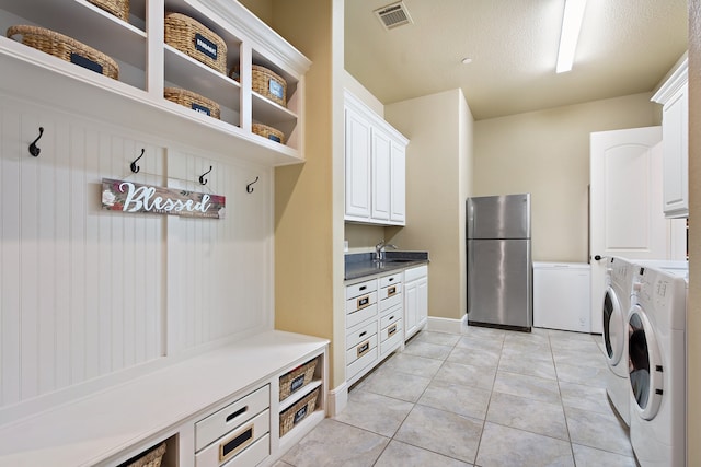 mudroom featuring sink, light tile patterned floors, a textured ceiling, and washer and clothes dryer