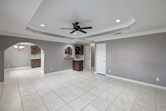 empty room with crown molding, ceiling fan with notable chandelier, a tray ceiling, and light tile patterned flooring