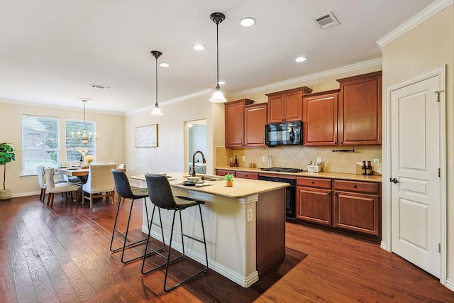 kitchen featuring pendant lighting, appliances with stainless steel finishes, an island with sink, dark wood-type flooring, and sink