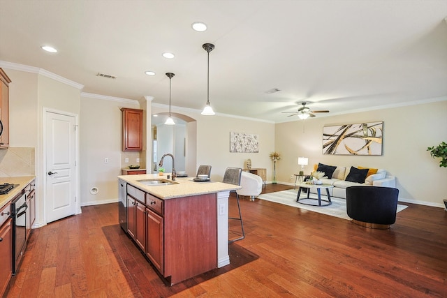 kitchen featuring decorative light fixtures, dark hardwood / wood-style flooring, sink, a breakfast bar area, and a kitchen island with sink