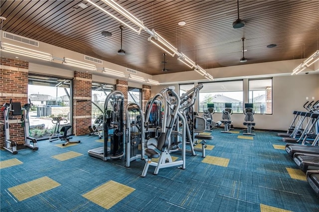 gym with wooden ceiling, dark carpet, and brick wall