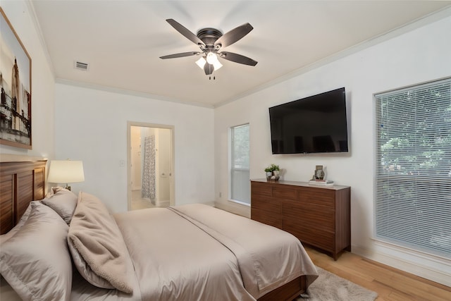 bedroom featuring crown molding, ensuite bath, light hardwood / wood-style flooring, and ceiling fan