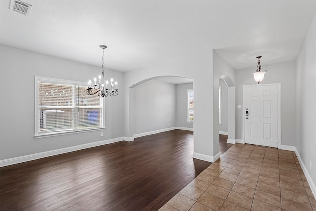 foyer entrance featuring a wealth of natural light, dark hardwood / wood-style flooring, and a notable chandelier