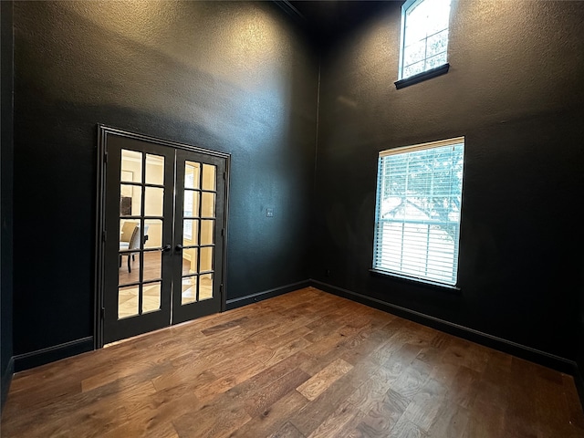 empty room with wood-type flooring, a wealth of natural light, and french doors